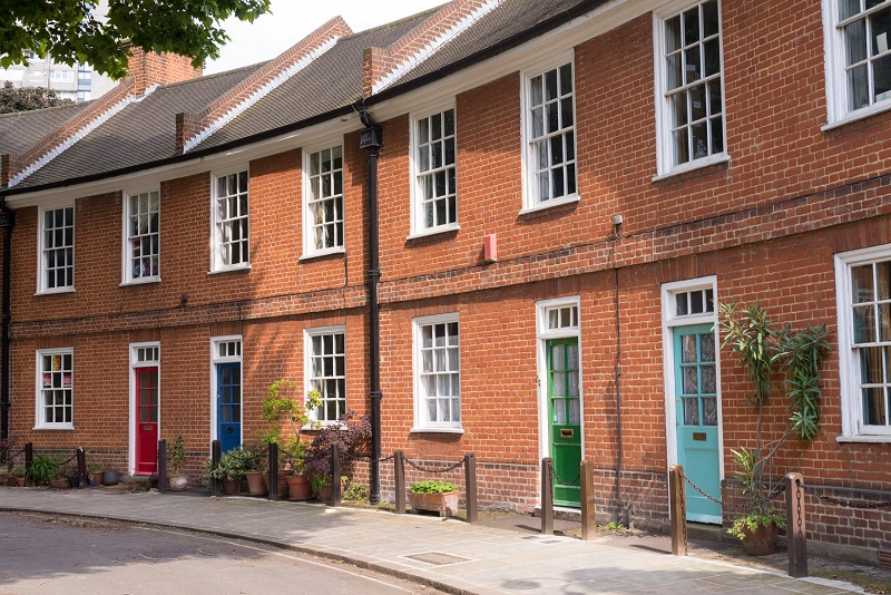 Restored Victorian red brick houses with coloured doors on a local road in London, UK