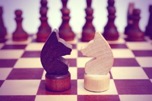 Two knight on a chessboard. Light and dark. Confrontation. Against each other. Forehead to forehead. Vintage toning.